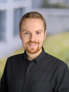 Profile photo of Paul. He has short blonde hair, brown eyes, a groomed beard, and is smiling in a dark grey button-down shirt against a blurred background.